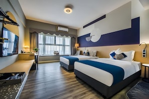 Habitació d'hotel amb dos llits, una taula de treball, una cadira, una finestra gran amb cortines i un televisor fixat a la paret.