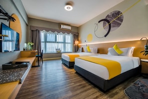 Habitación de hotel con dos camas, un escritorio, un televisor y un ventanal grande.