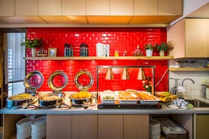 Un aparador tipus buffet amb diversos plats, un respatller de rajoles vermelles i armaris de fusta.