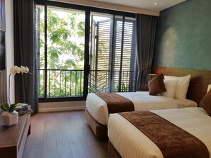 A hotel room with two beds, a view of greenery outside, and a small table with a plant. - Orchid Boutique Hotel and Apartment (Nha Trang)