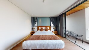 A modern hotel room with a large bed, a wooden headboard, and a view through a glass door. - Orchid Boutique Hotel and Apartment (Nha Trang)