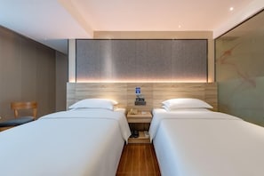 A hotel room with two beds, a wooden headboard, a small table with a phone and a lamp, and a chair. - Winsome Hotel Guangzhou Tianhe Huajing Road Metro Branch (Shenzhen)