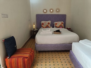 Een hotelkamer met een bed, nachtkastje, lamp, stoel en een vloer met patroon.