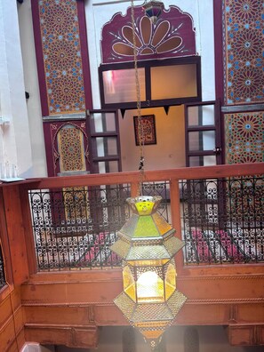 A balcony with ornate metal railings, a hanging lantern, and decorative wall panels.