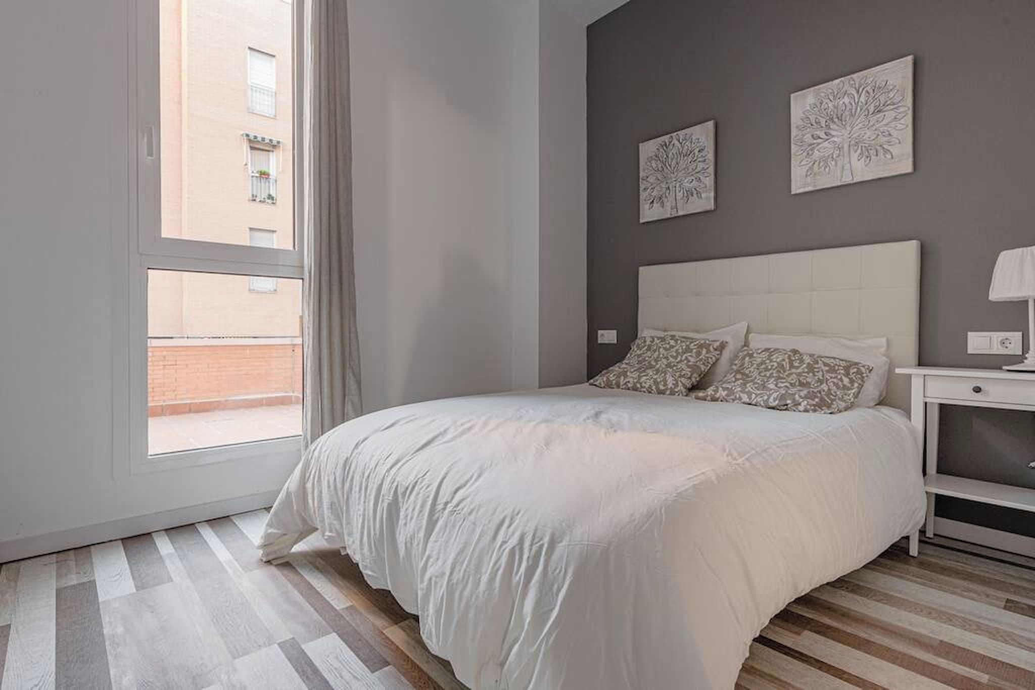 Ein Schlafzimmer mit einem großen Bett, einem Nachttisch und zwei an der Wand befestigten Kunstwerken.