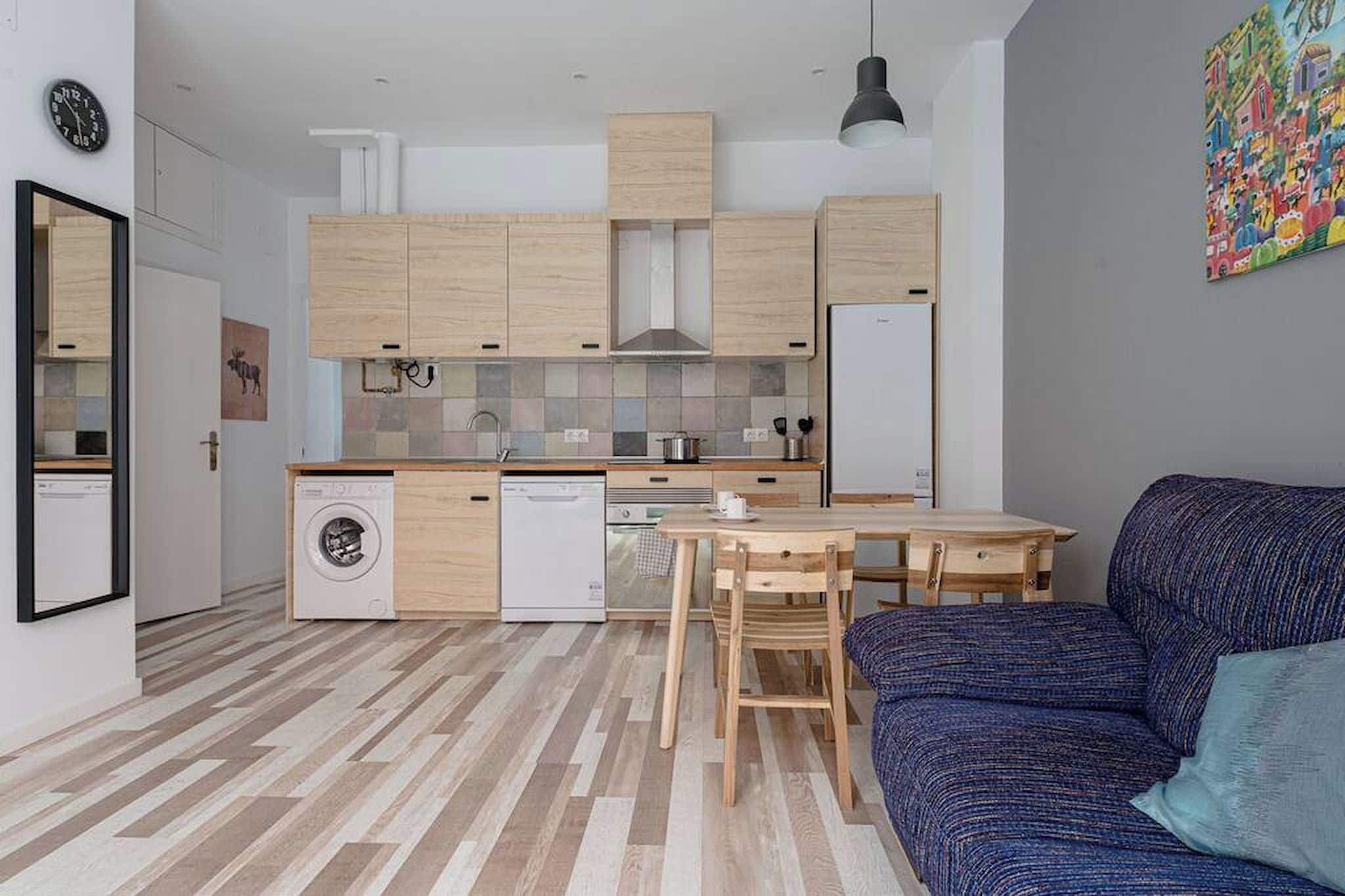 Eine kompakte Küche mit Holzausstattung, einem Geschirrspüler und einem Essbereich mit Tisch und Stühlen.