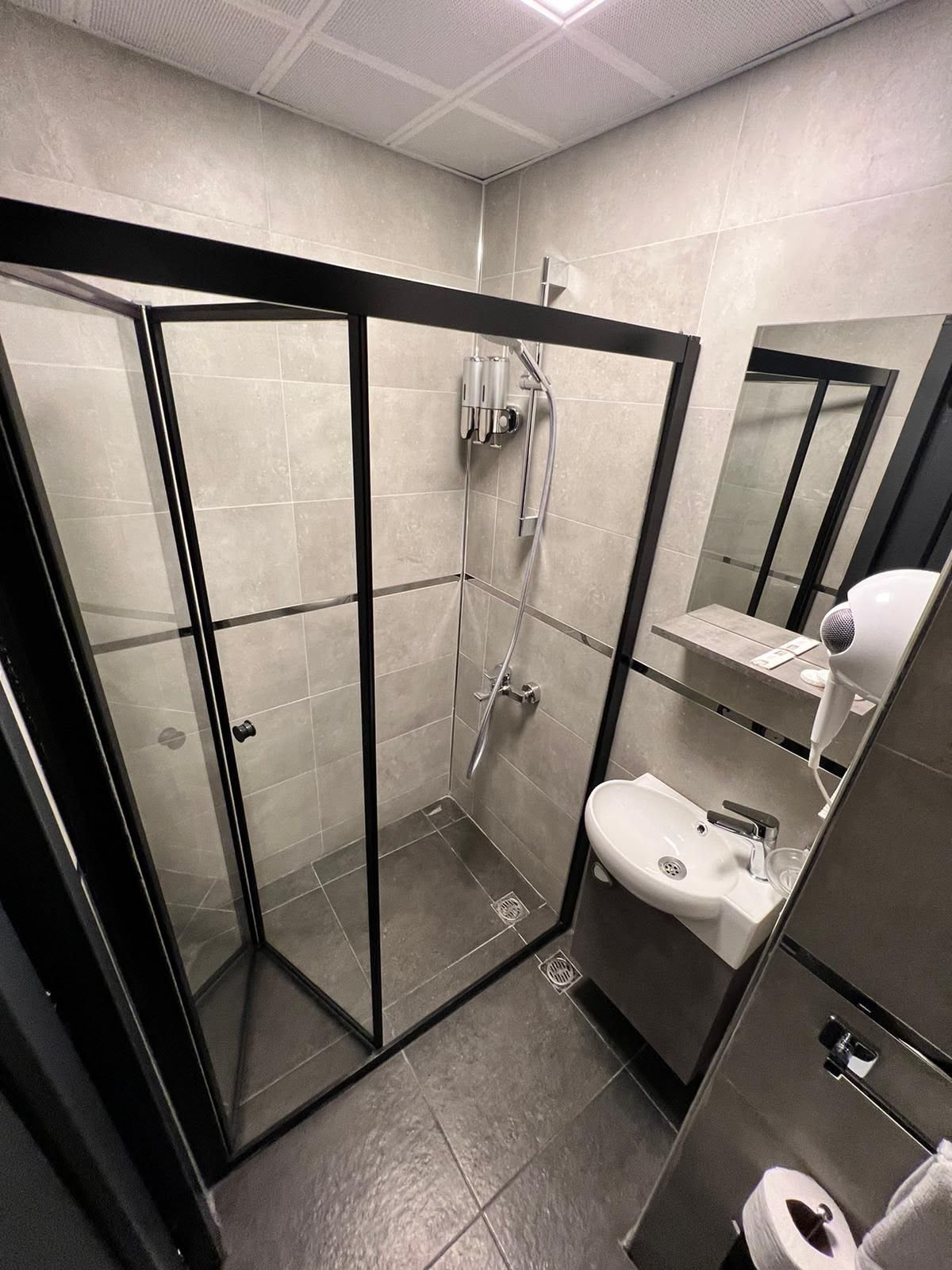 Un baño moderno con ducha de vidrio, lavamanos e inodoro.