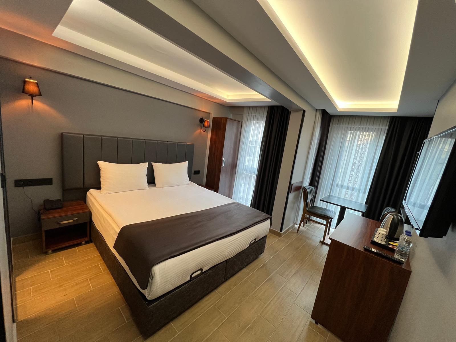 Una habitación de hotel moderna con una cama grande, mesitas de noche, un escritorio con silla y un televisor.