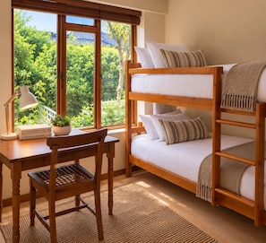 A bunk bed with a desk and chair, a lamp, and a window with a view of greenery. - 6 Bond St (Knysna)