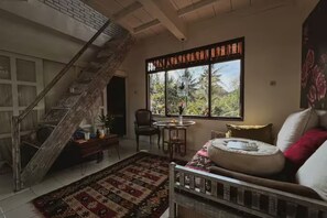 A room with a staircase, a large window with a view, a sofa, and a patterned rug. - Rare 2-Level Jungle Loft · Walk to Alchemy Yoga_BRAHMA (Kecamatan Ubud)