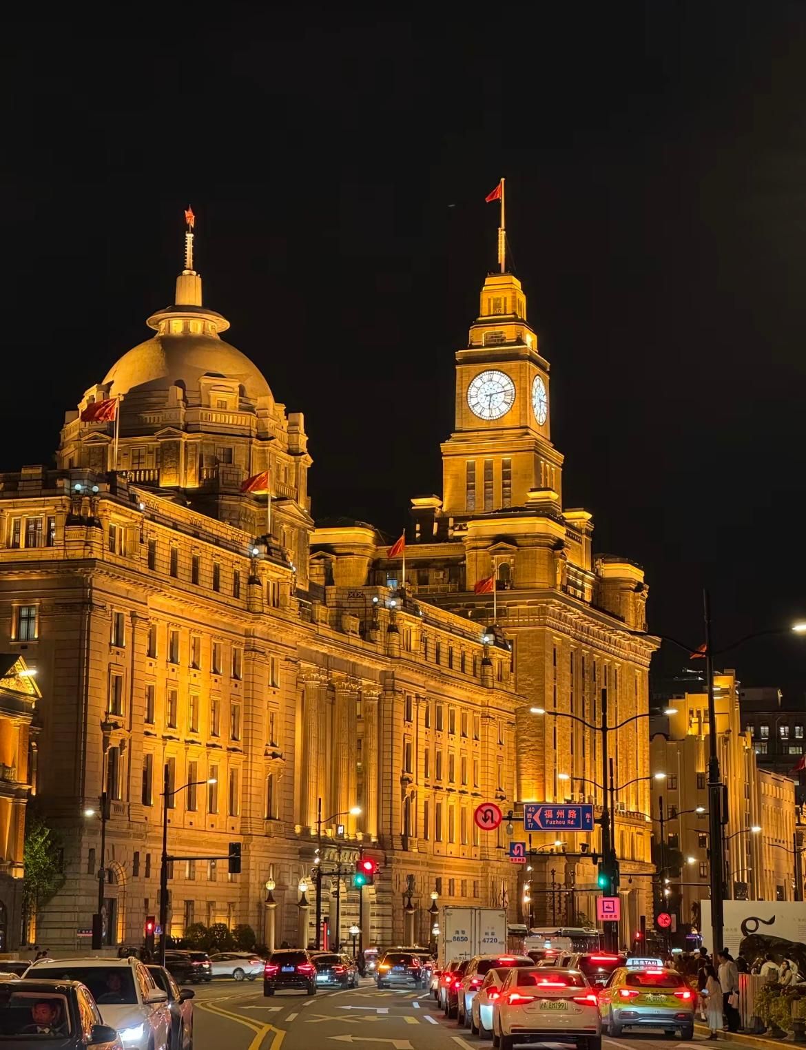 A grand building with a prominent clock tower and a large dome, surrounded by busy streets and traffic.