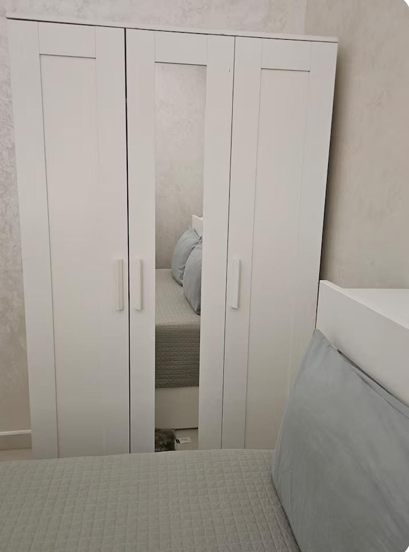 Une chambre à coucher avec un lit, une armoire et une table de chevet.