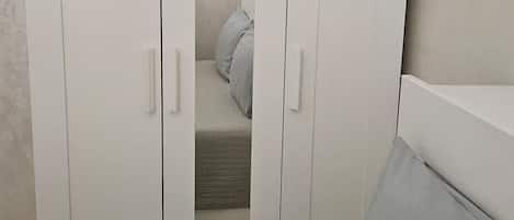 A bedroom with a bed, a wardrobe, and a bedside table.