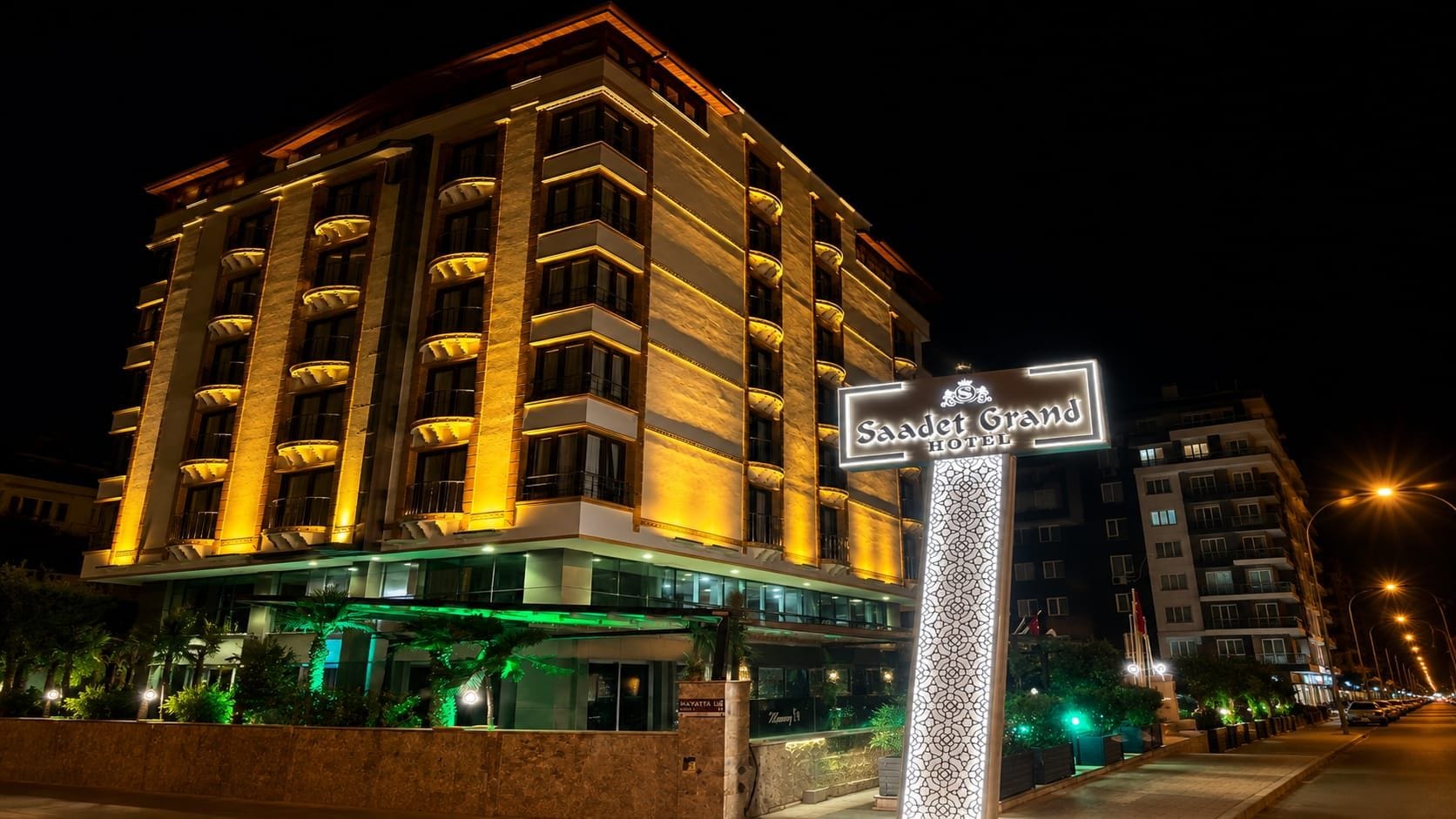 A multi-story hotel with a prominent sign, balconies, and a well-lit entrance.
