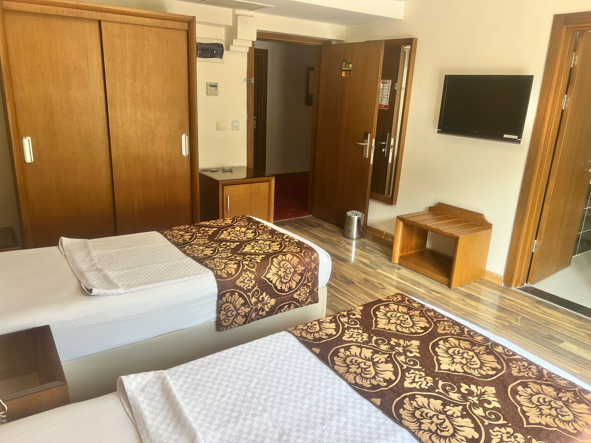 Una habitació d'hotel amb dos llits, una taula, una cadira, un televisor i un armari.
