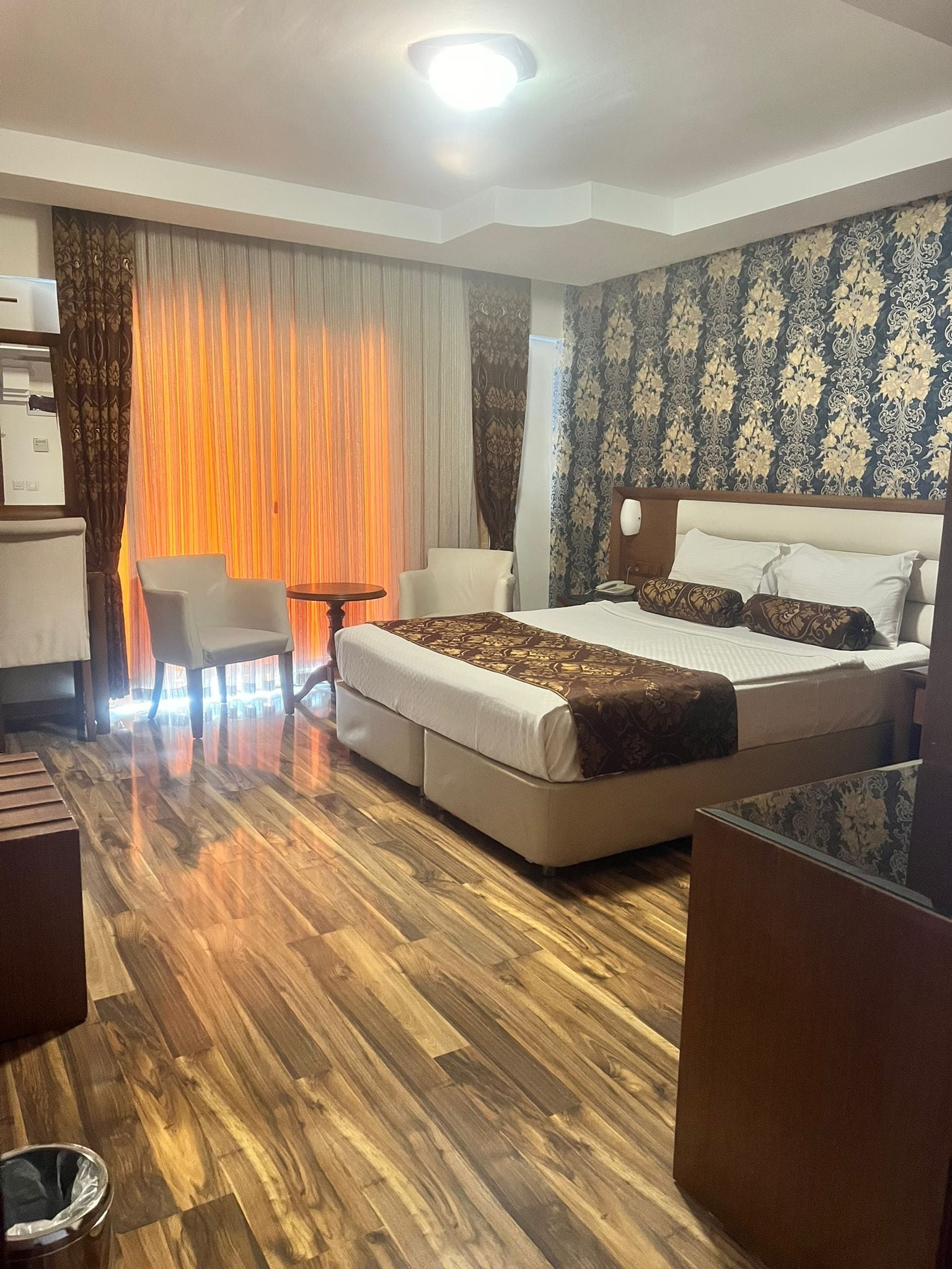 A hotel room with a bed, a desk, a chair, and a small table.