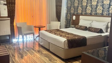A hotel room with a bed, a desk, a chair, and a small table.