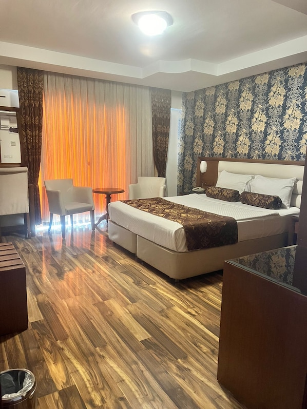 A hotel room with a bed, a desk, a chair, and a small table.