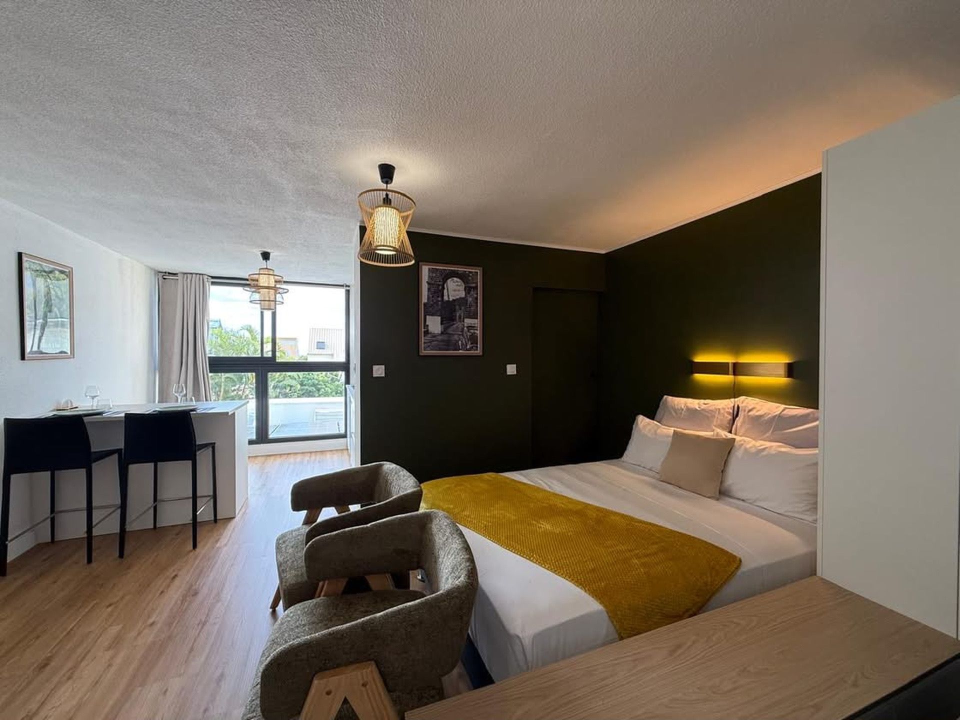 A modern hotel room with a bed, a desk, and a dining area.