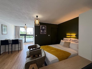A modern hotel room with a bed, a desk, and a dining area. - New Listing (Saint-Denis)
