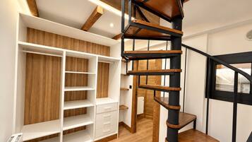 Un intérieur moderne avec un escalier en colimaçon, des étagères en bois intégrées et un radiateur.