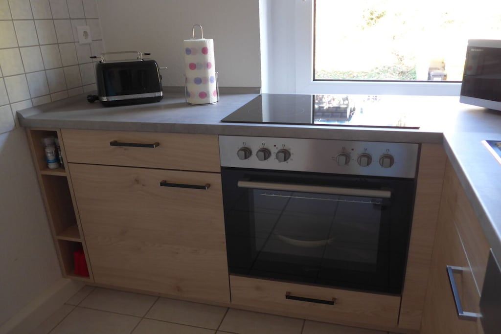Cozinha equipada com forno embutido, torradeira e janela.