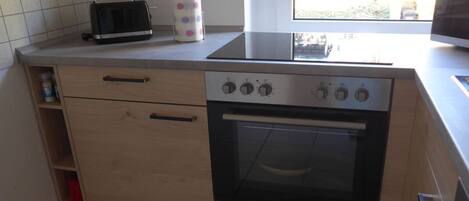 A kitchen with a built-in oven, a toaster, and a window.