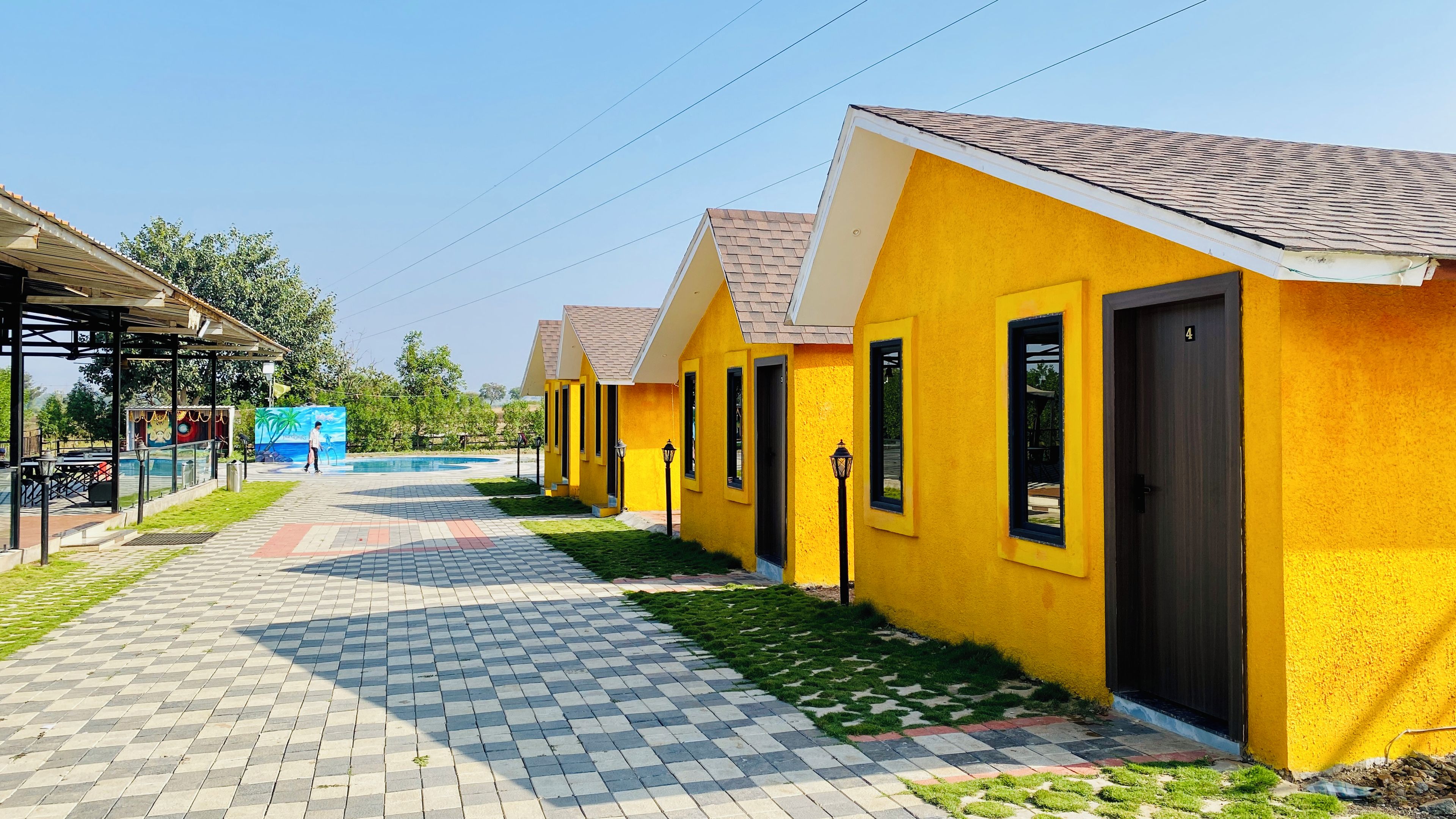 A row of yellow buildings with a tiled walkway leading to a pool area.