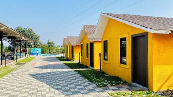 A row of yellow buildings with a tiled walkway leading to a pool area.