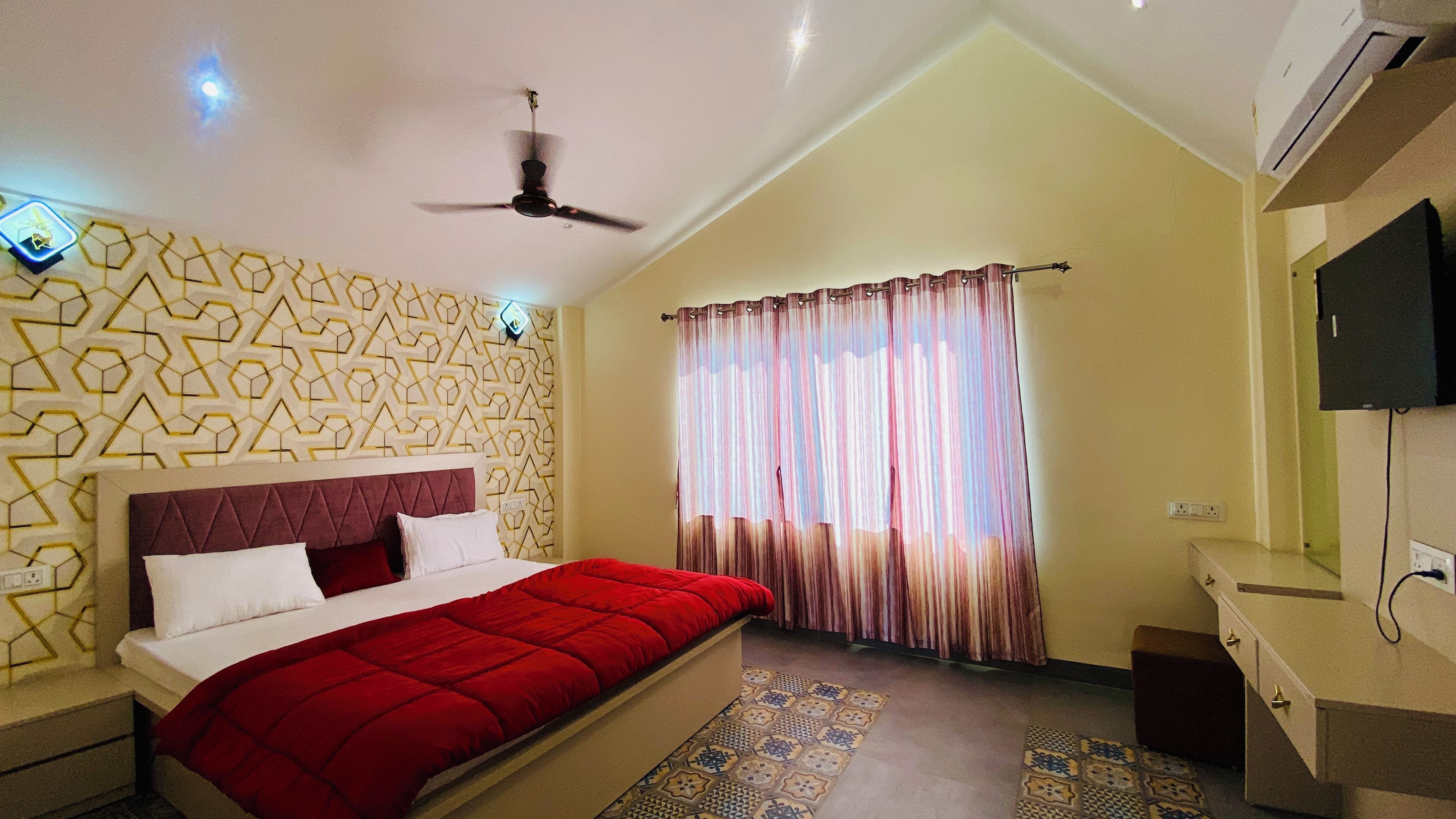 A bedroom with a bed, a ceiling fan, a window with curtains, a TV, and a patterned wall.