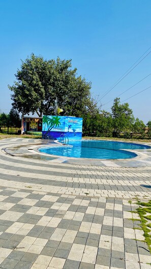 Una piscina con un borde de baldosas y un mural que representa una escena de playa.