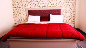 Cama com colcha vermelha, cabeceira e parede estampada.