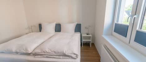 A bedroom with a bed, bedside table, and a window.