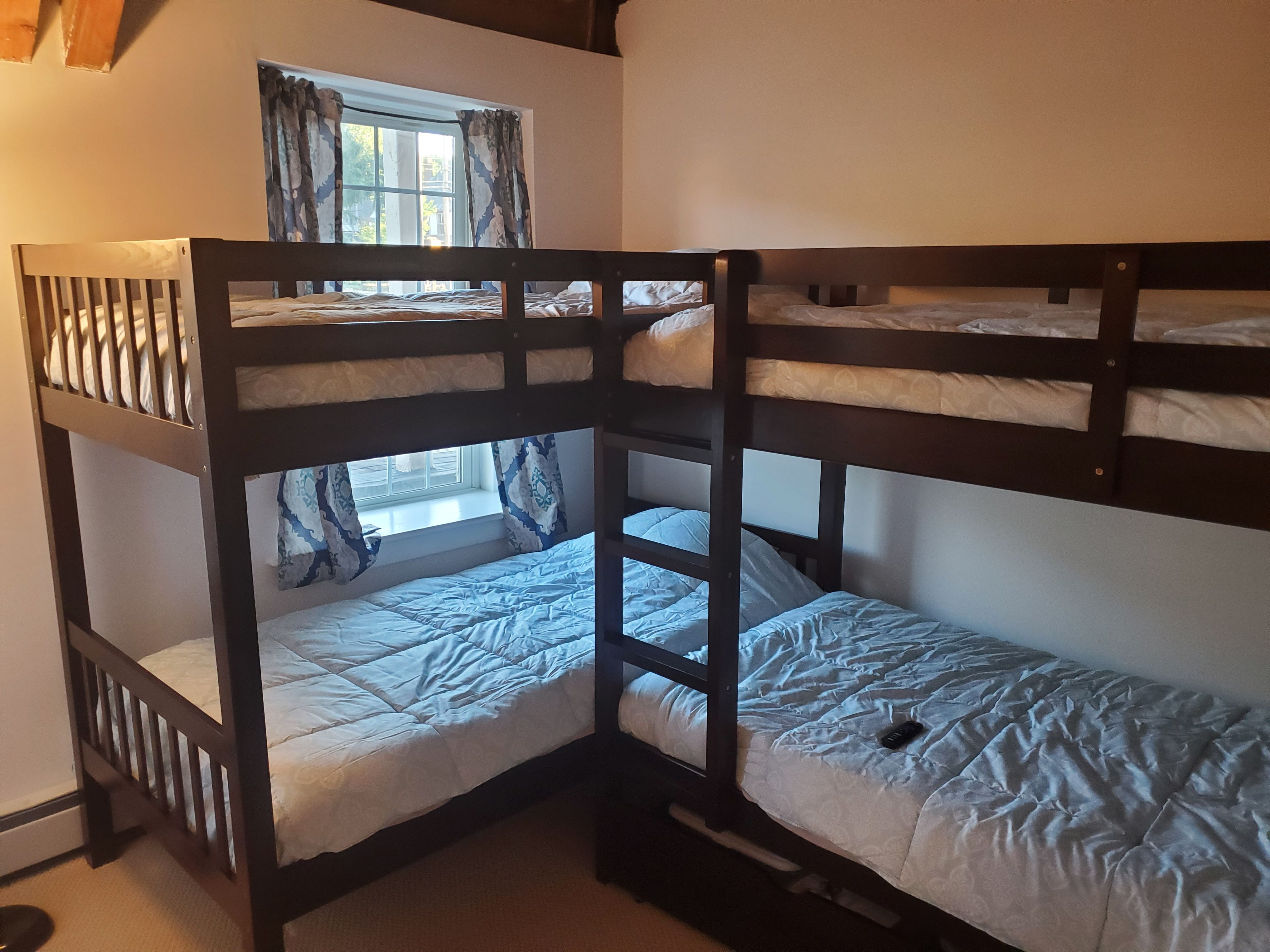 A bunk bed room with a window and curtains.