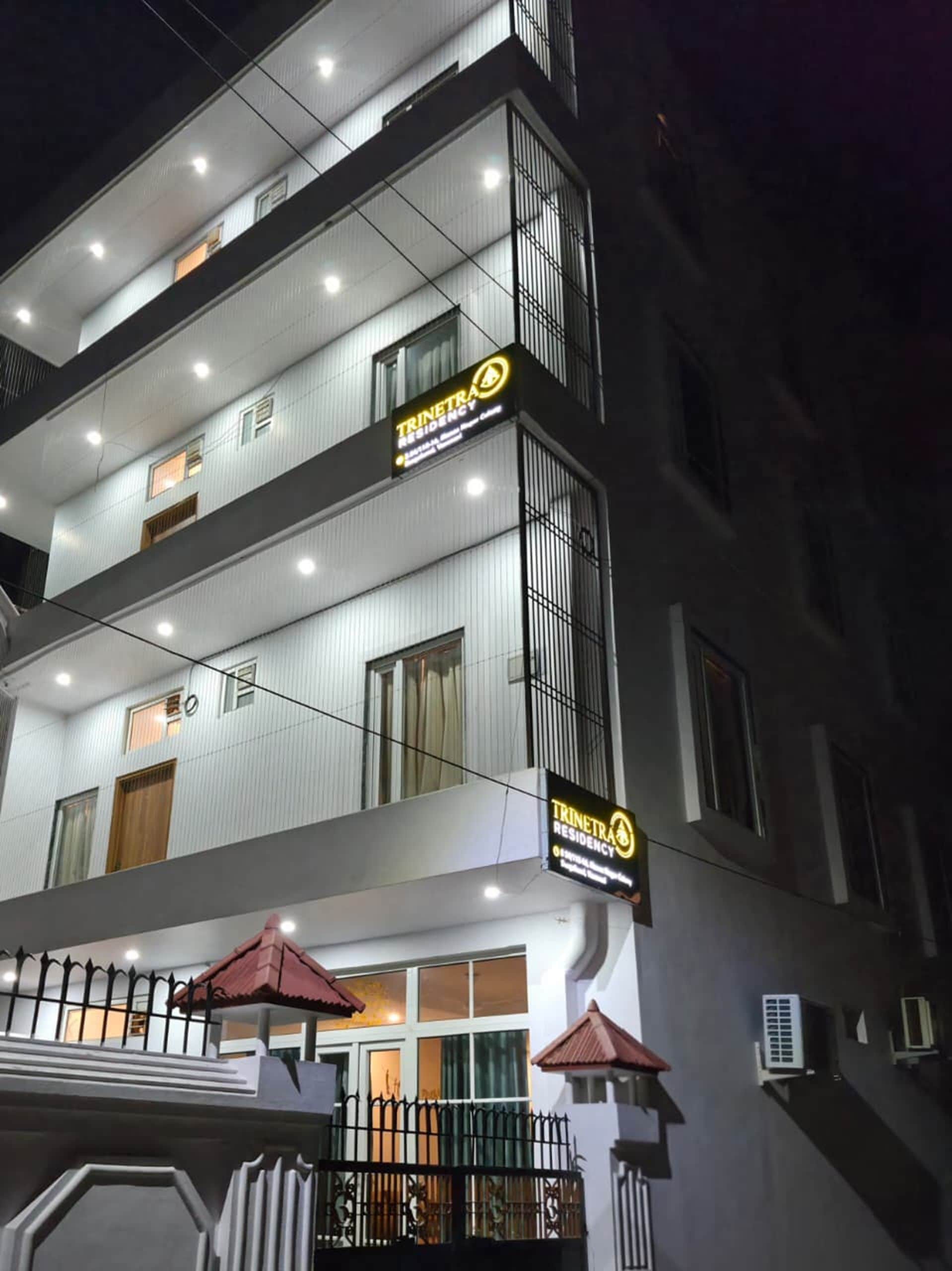 Un edificio de varios pisos con balcones, un cartel que indica que es una residencia y una entrada con puerta de reja.