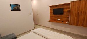 Un dormitorio con una cama, un televisor montado y un armario de madera.