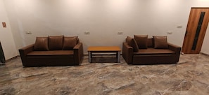 A room with two brown leather sofas, a small wooden table, and a stone-patterned floor.