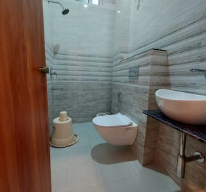 Un baño con pared de mármol, inodoro, bidé y lavamanos.