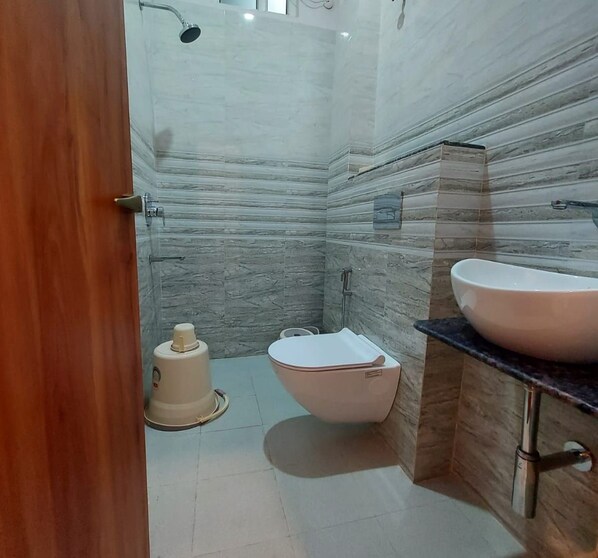 A bathroom with a marble wall, a toilet, a bidet, and a sink.