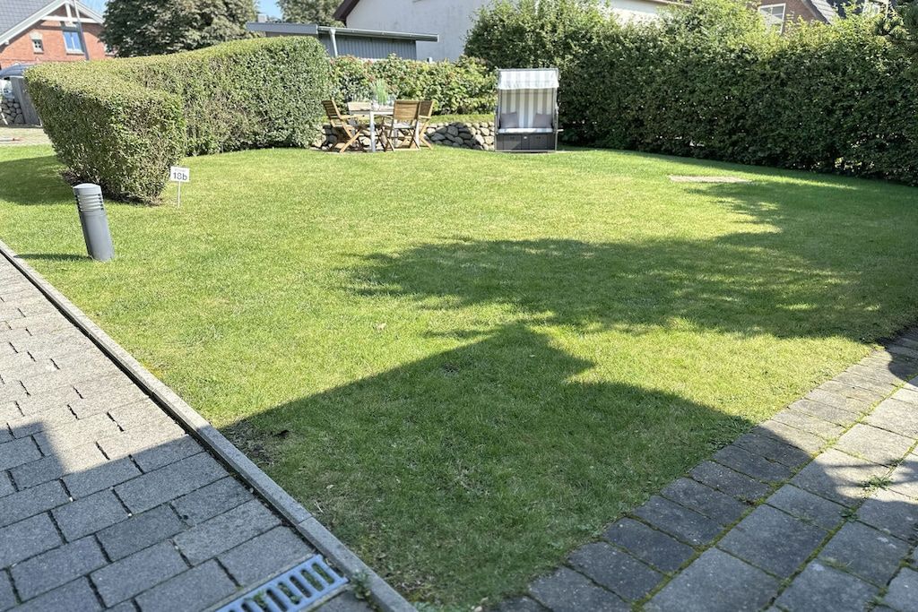 A well-maintained lawn with a patio area, outdoor furniture, and a grill.