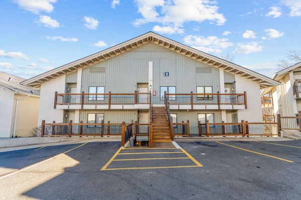 A two-story building with a central staircase, a parking lot, and a clear sky. - Step Free Access 2BR Condo • Balcony • Pools • Walk to Branson Landing (Branson)