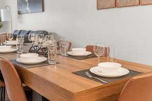 Tavolo da pranzo apparecchiato con piatti bianchi, bicchieri e posate, caratterizzato da un design moderno e una palette colori neutra.