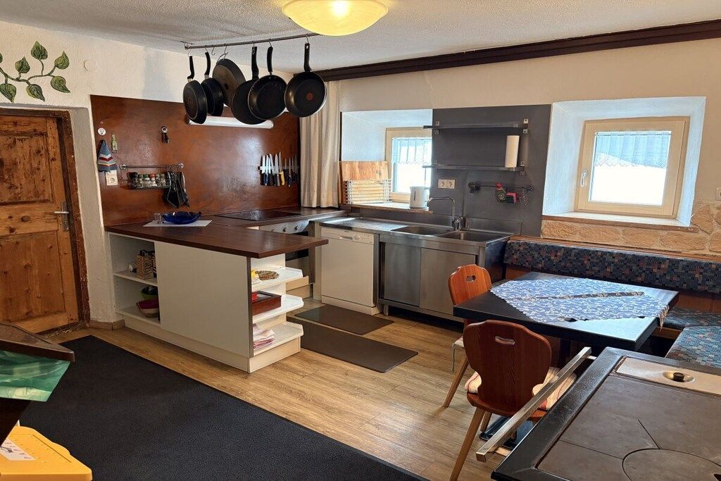 Kompakti keittiö, jossa on sisäänrakennettu liesi, ruokailutila penkillä ja ikkuna, josta on näkymä.