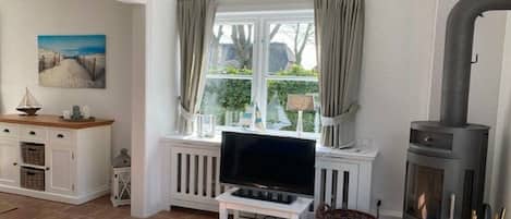 Un salon confortable avec une télévision, une cheminée et une fenêtre avec des rideaux.
