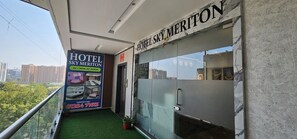 Pasillo de hotel con un cartel que indica Hotel Sky Meridian, que ofrece habitaciones con aire acondicionado y sin aire acondicionado, número de contacto y vistas panorámicas de la ciudad.