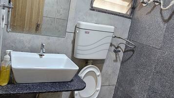 Un baño con inodoro, lavamanos, espejo y ducha.
