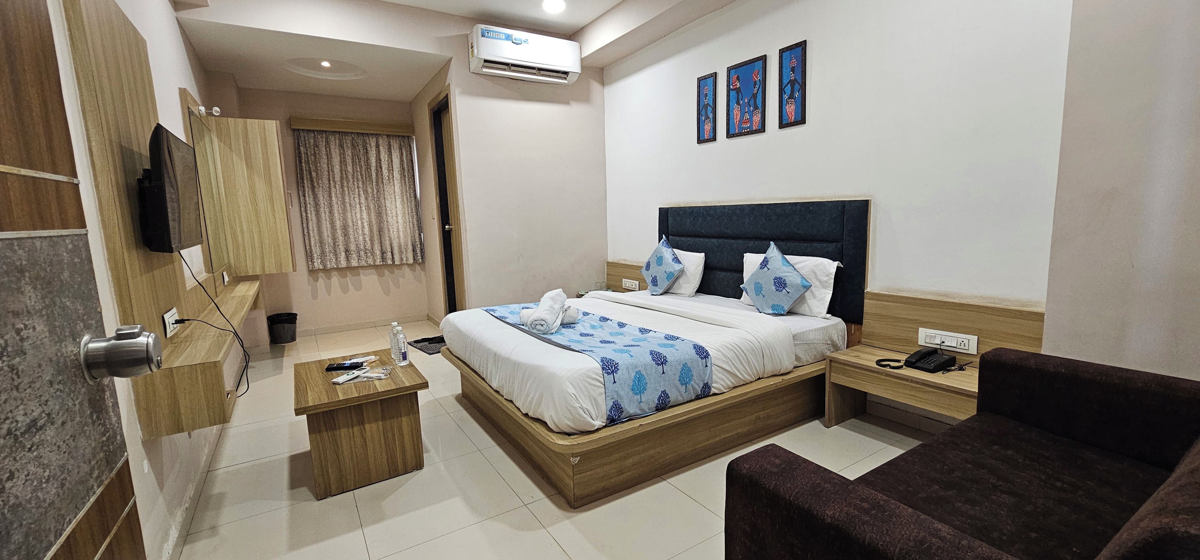 Habitación de hotel con cama, mesita de noche, silla y televisor.