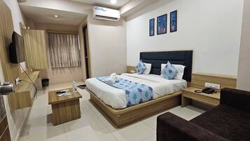 Habitación de hotel con cama, mesita de noche, silla y televisor.
