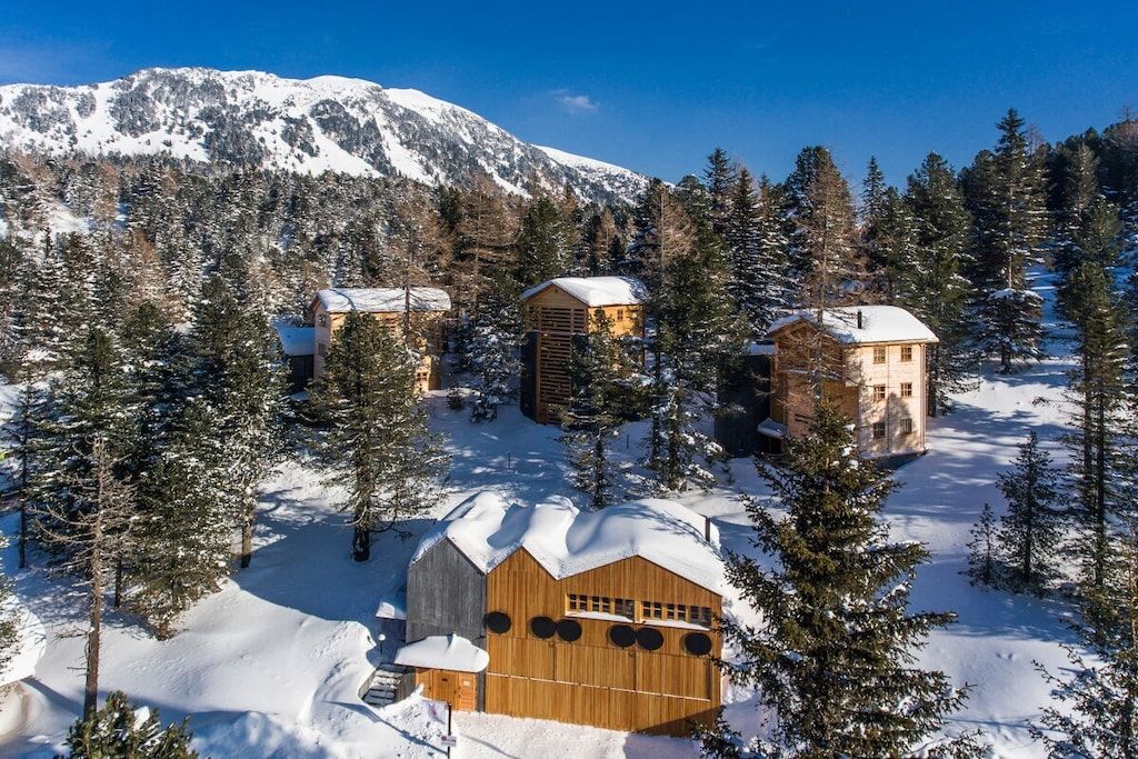 A snow-covered mountain landscape with wooden cabins surrounded by trees.