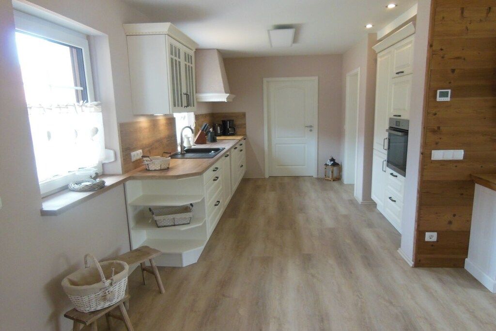 A kitchen with white cabinets, a wooden countertop, a sink, and a stove.